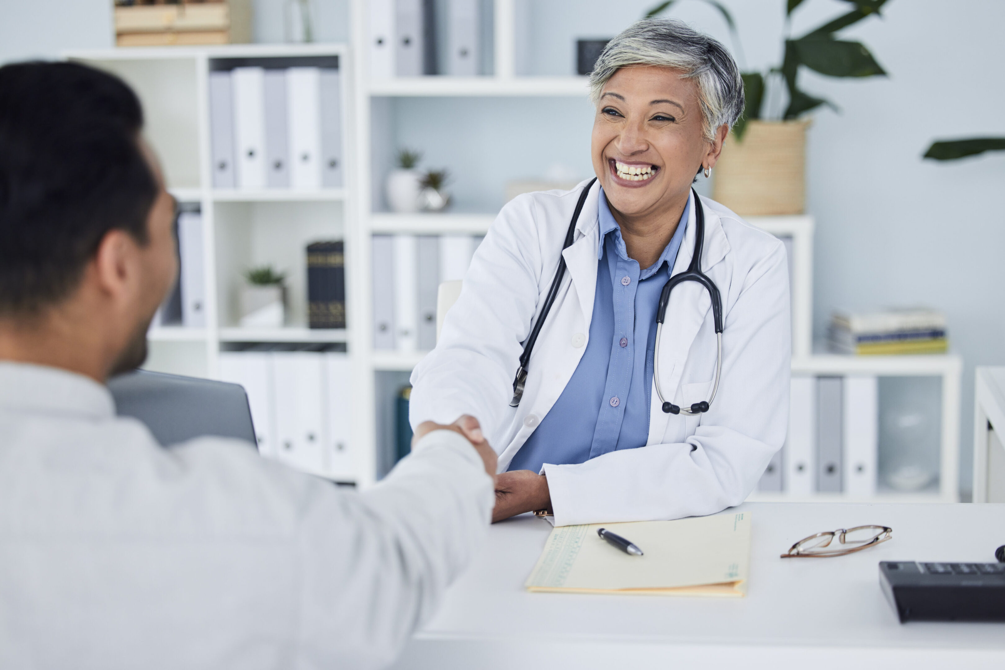 Happy woman, doctor and handshake for meeting, hiring or partnership in consultation at the hospital. Senior female person, medical or healthcare professional shaking hands in interview or recruiting Restore Health Family Practice